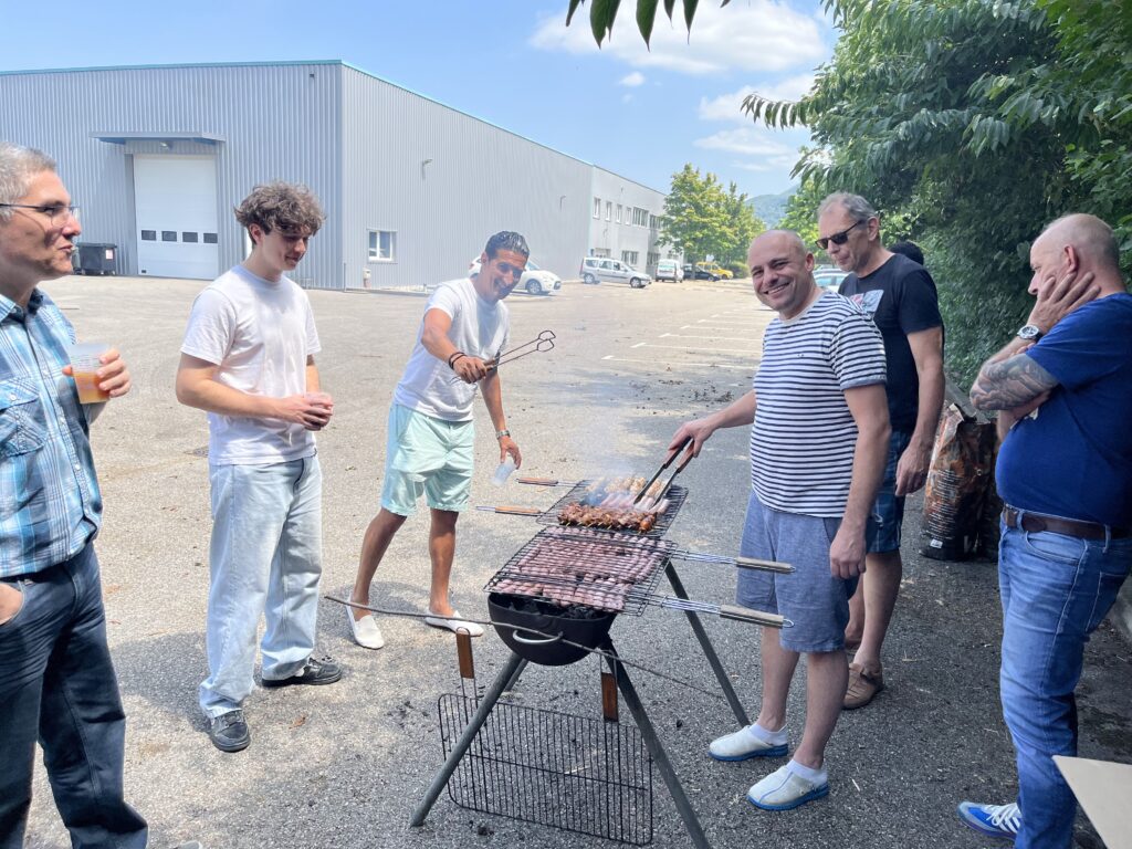 Des collaborateurs de MAATEL réunis en extérieur autour d’un barbecue, partageant un moment convivial lors d’un événement d’équipe.